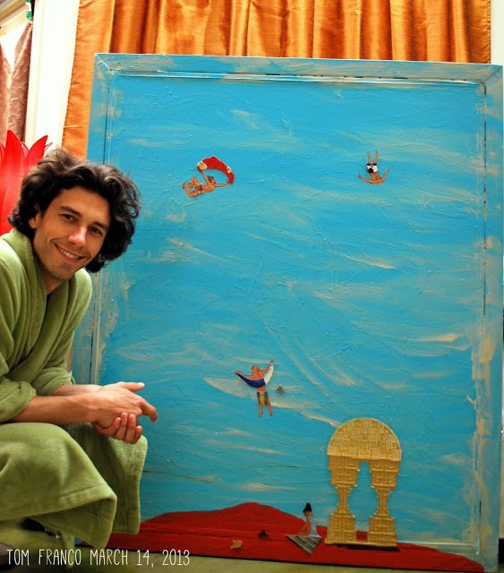 Tom Franco in dressing gown, next to art.