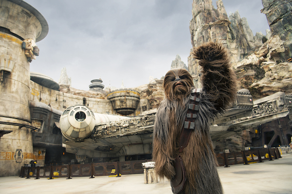 Chewbacca standing in front of the Millennium Falcon at Star Wars: Galaxy’s Edge at Walt Disney World Resort in Florida