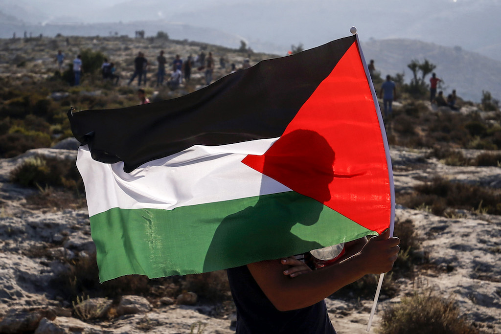 TOPSHOT - A Palestinian protester waves a Palestinian flag during a demonstration in the village of Ras Karkar west of Ramallah in the occupied West Bank on September 4, 2018. (Photo by ABBAS MOMANI / AFP) (Photo credit should read ABBAS MOMANI/AFP via Getty Images)