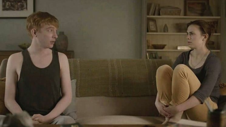 A still from 'Black Mirror' episode 'Be Right Back. A man and woman sit on a couch together. 