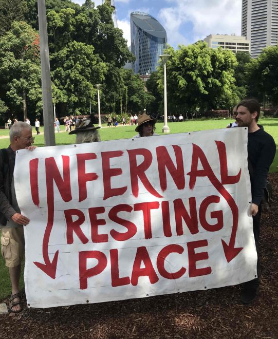 Four protesters holding a giant sign which reads "Infernal Resting Place"