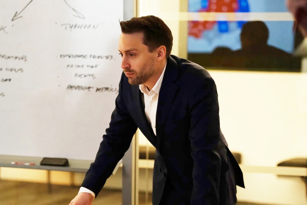 Kieran Culkin leaning against a table in succession episode 8