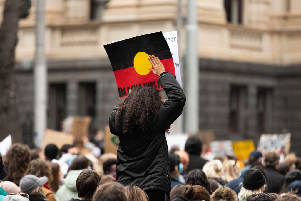 Uluru Youth Dialogue Voice to Parliament Person Holding Indigenous Flag