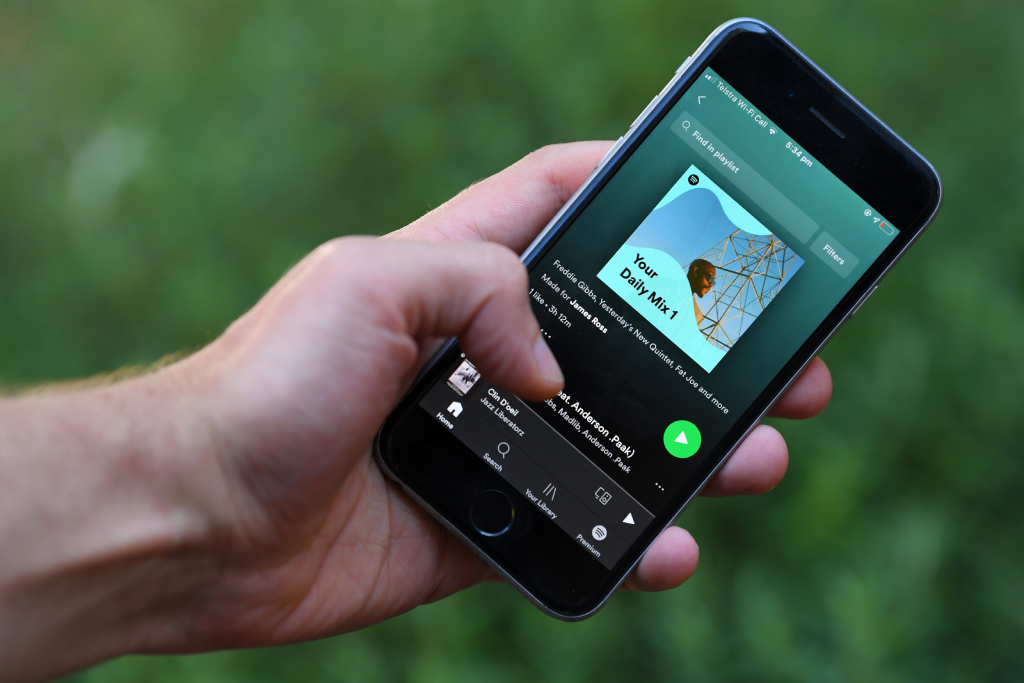 a hand holding a phone playing music with spotify